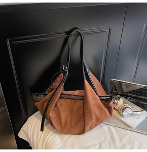 Detail view of brown matte suede tote with black leather strap and zipper closure