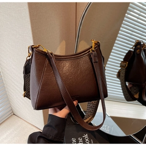 Close-up of vintage brown leather bag with retro gold hardware and woven strap