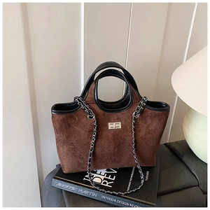 Detail of brown suede tote bag featuring diamond pattern embossing and metal chain strap