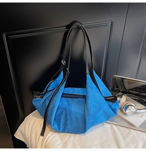 Detailed texture of blue suede tote bag with black handles and metal zipper closure