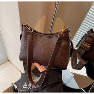 Detail of vintage brown shoulder bag with detachable ethnic woven strap and golden hardware