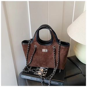 Close-up of retro brown suede tote with quilted stitching and silver metal twist lock