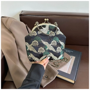 Macro detail of elegant crane embroidery on vintage dark silk cross-body kiss lock bag