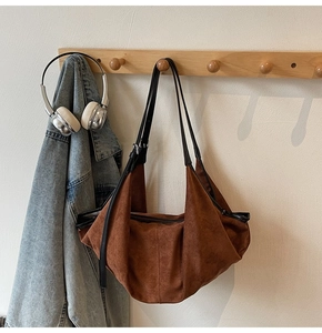 Detail of vintage brown suede tote bag featuring slim black shoulder strap and soft texture