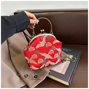 Macro detail of red silk crane embroidery and antique copper metal frame on the bag