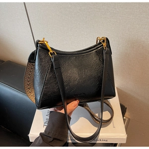 Detail of lychee pattern leather underarm bag with gold metal buckle and woven strap
