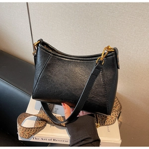 Detail of black crescent shoulder bag with branded logo and textured jacquard strap