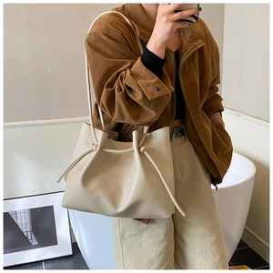 Detail view showing the unique knotted handle and soft texture of the cream tote bag