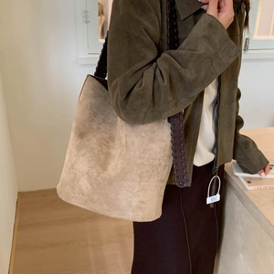 Detail of woven brown leather strap on a beige suede shoulder tote bag for women