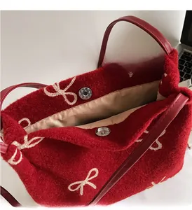 Détail du sac cabas en feutre rouge avec fermoir magnétique et broderie de nœud blanc