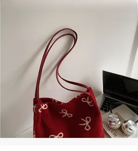 Détail du sac cabas rouge avec broderies nœuds blancs et fines bandoulières sur bureau