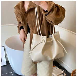 Detail of off-white minimalist tote bag featuring drawstring knots and leather texture