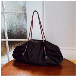 Détail du sac cabas plissé noir avec bandoulière en corde tressée rouge et gris