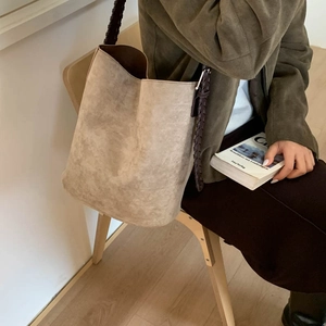 Detail of vintage beige suede tote bag with brown woven leather strap on a chair