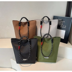Detail view of four colorful checkered canvas tote bags with woven rope handles on white display