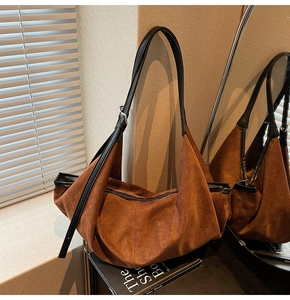 Detail view of the brown suede hobo bag with a black adjustable leather strap and zip closure