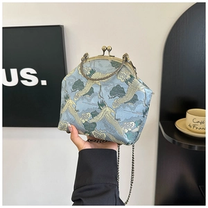 Macro detail of crane embroidery on light blue silk brocade kiss lock bag with bronze frame