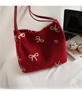 Gros plan d'un sac bandoulière en peluche rouge avec broderies de nœuds blancs élégants