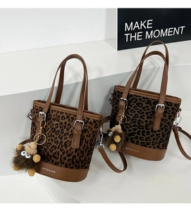 Detailed close-up of leopard print tote bag featuring brown leather base and fuzzy charm