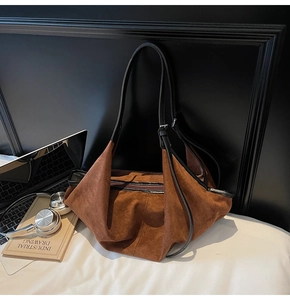 Detail of vintage brown suede tote bag with black leather straps and top zipper closure