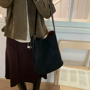 Detail view of black vintage suede bucket bag with unique woven shoulder strap and brown lining