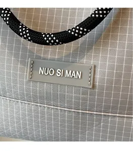 Macro detail of grey mesh shoulder bag featuring braided handles and a minimalist logo patch