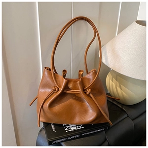 Nahaufnahme der braunen Vintage-Tasche mit Litschi-Struktur auf einem Designbuch