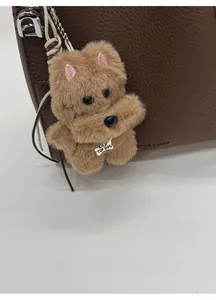 Close-up of plush brown dog bag charm with pearl necklace on brown leather bucket bag