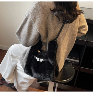 Dettaglio borsa a secchiello in peluche nera con chiusura in metallo su maglione a maglia