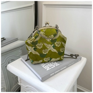 Close-up of a dark green silk bag with white crane embroidery and vintage metal clasp
