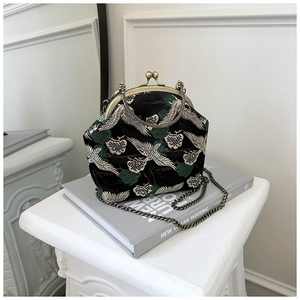 Detail of elegant white crane embroidery and pine needles on a black satin purse