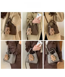 Close-up of pebble leather bucket bag with cute bear charm and adjustable shoulder strap