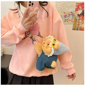 Detail of yellow plush bear crossbody bag with lace hat worn on a model outfit