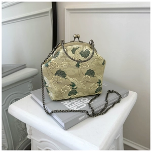 Detail of elegant crane embroidery and vintage bronze metal clasp on a brocade bag