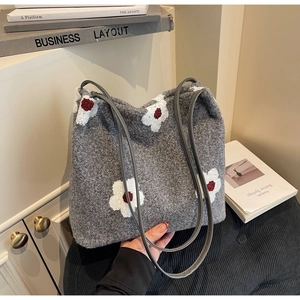Detailed close-up of grey plush tote bag featuring floral patterns and leather handles