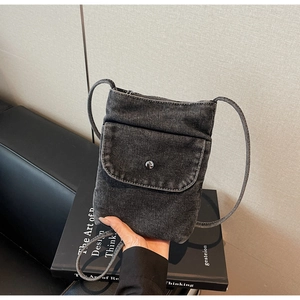 Close-up of black denim crossbody phone bag with metal snap and thin shoulder strap