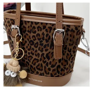 Close-up of leopard print bucket bag with brown leather trim and plush monster charm