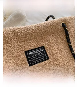 Détail macro du sac cabas en peau de mouton beige avec logo et bandoulière tressée