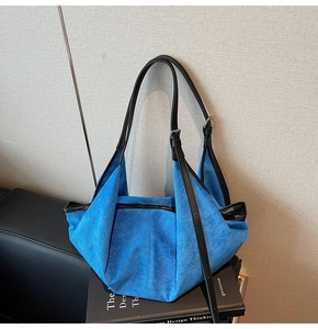 Detail of bright blue suede hobo bag with adjustable black leather shoulder strap