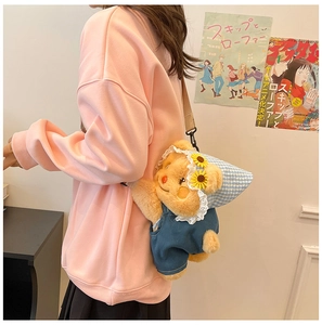 Detail view of a cute plush bear bag wearing blue overalls and a floral sun hat