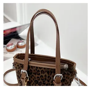Close-up of leopard print bucket bag with brown leather handles and silver metal hardware