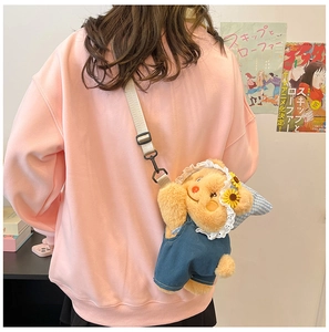Detail of cute bear plush crossbody bag in denim overalls shown on female model