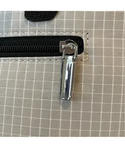 Macro shot of silver metal zipper puller on gray checkered fabric tote bag surface