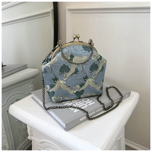 Detail of crane embroidery and bronze metal kiss lock on retro blue jacquard crossbody bag