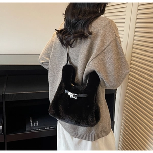 Dettaglio di una borsa nera in peluche con chiusura in metallo argento e texture in pelliccia
