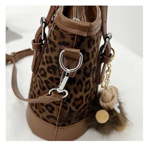 Detail view of leopard print bucket bag with brown leather trim and silver metal hardware