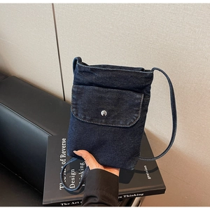 Detail of dark blue denim phone bag with silver button closure and slim shoulder strap