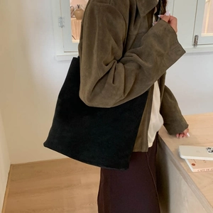 Detailed view of large black suede tote bag with minimalist shoulder strap on model