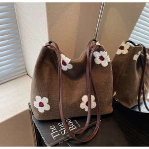 Detailed embroidery on brown plush bucket bag with leather strap and floral pattern