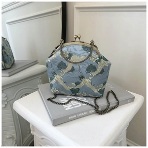 Close-up of crane embroidery on light blue brocade with bronze metal kiss lock